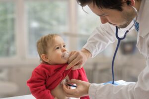 Pediatrician doctor is examining child with stethoscope.